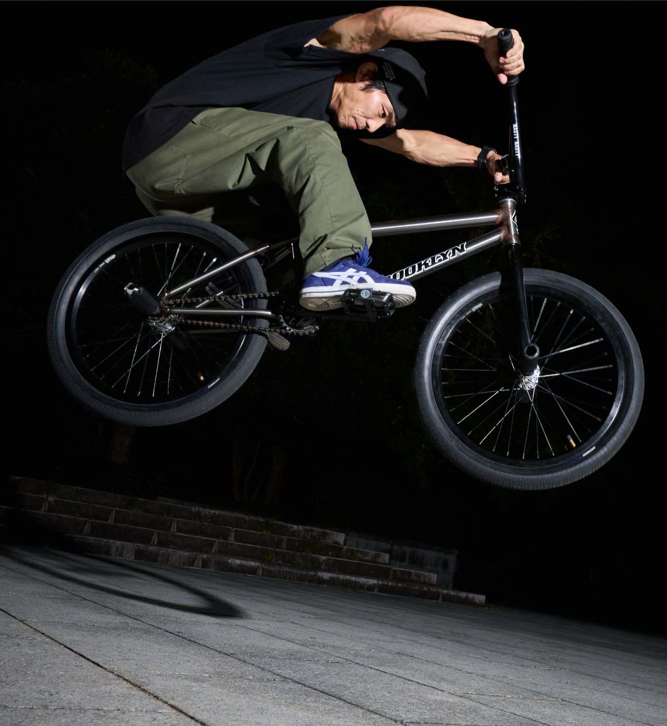 夜のパークでBMXに乗ったままジャンプするライダー