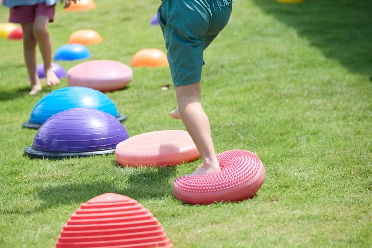 はだしでバランス遊具の上を歩く子ども