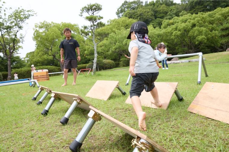 はだしで木の板を駆け上がる子ども